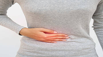 Urologenzentrum Wien - Leistenbruch bei einer Frau, die ihre Hand auf den Unterbauch hält.