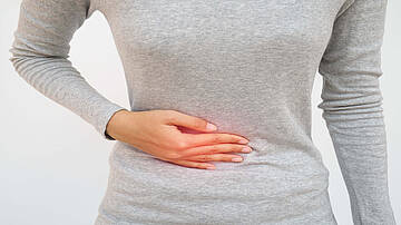 Urologenzentrum Wien - Leistenbruch bei einer Frau, die ihre Hand auf den Unterbauch hält.