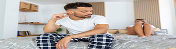 Testosteronmangel - Mann im Schlafzimmer mit Partnerin. Urologenzentrum Wien - Testosteronmangel bei einem Mann im Schlafzimmer mit Partnerin.
