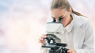 Wissenschaftlerin untersucht eine Probe unter dem Mikroskop.