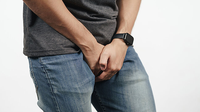 Verletzung am Penis - Schmerzhafte Verletzung im Unterbauchbereich. Urologenzentrum Wien - Verletzung am Penis: Mann hält sich schmerzerfüllt den Unterbauchbereich.